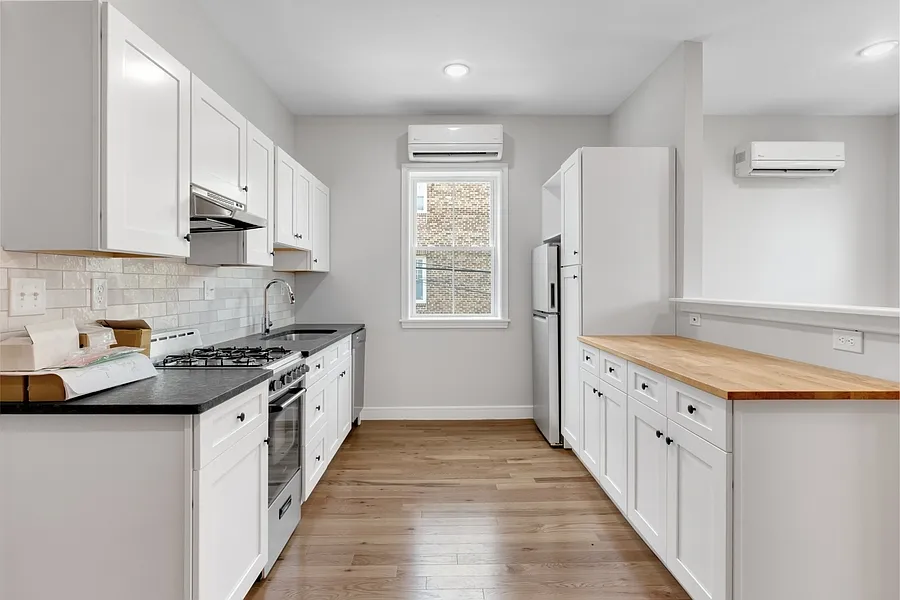 Modern kitchen has tile backsplash, stainless steel appliances, and shaker cabinets.