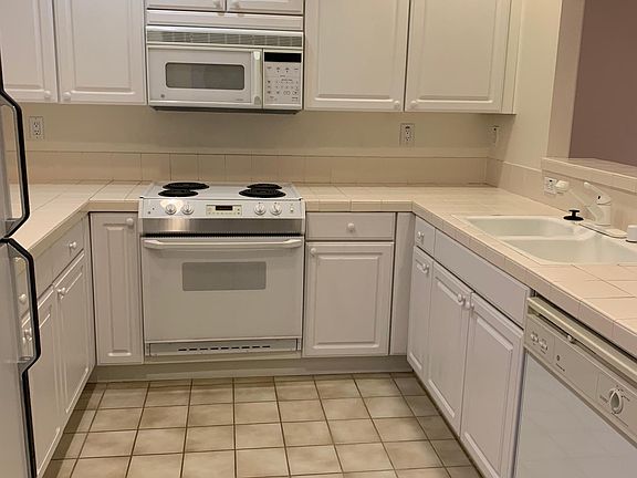 Kitchen with electric stove, oven, microwave, dishwasher, disposal, double sink and refrigerator.