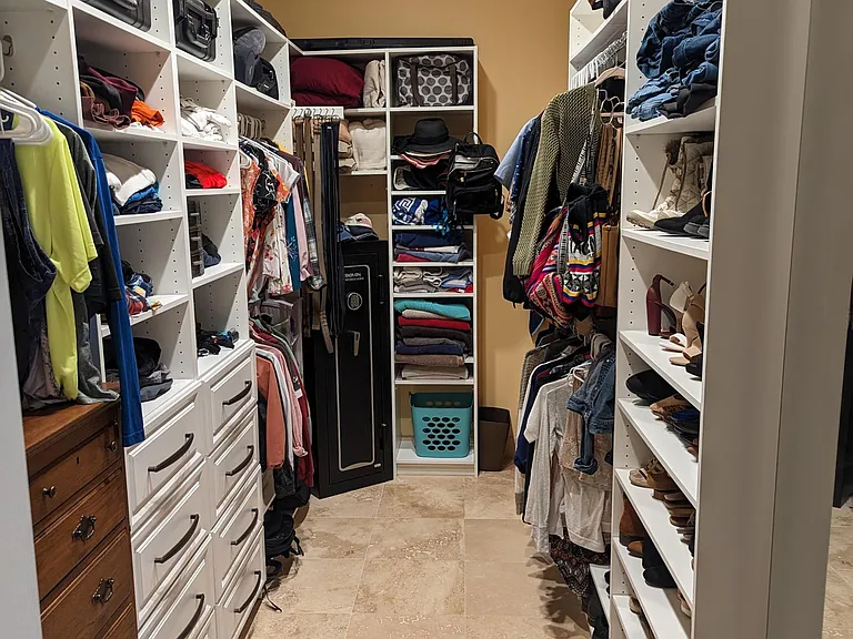 Master Suite, walk-through closet. This closet is impressive and boasts plenty of storage space for the clothing, shoes and other accessories of the Master Suite's occupants. It includes a full-size mirror, recessed lighting and doors on either end.