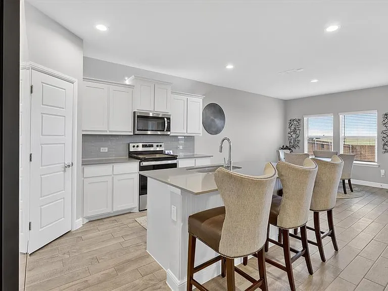 Kitchen featuring white cabinetry, stainless steel appliances, a tiled backsplash, a central island with a sink, and recessed lighting