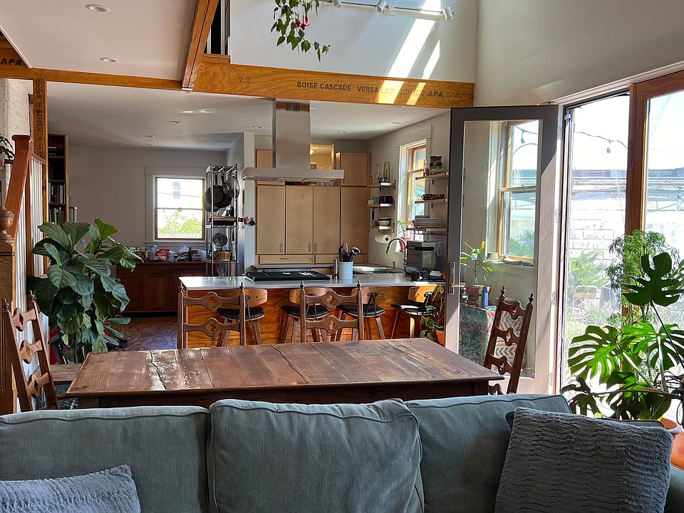 View from living room through dining room to kitchen and entry way, with stairs to the upper level and french doors to the garden and patio in the backyard.