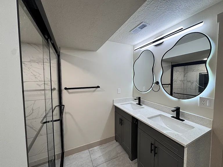 master bathroom with a double sink vanity and sleek LED lighted mirrors, creating a bright and modern atmosphere.