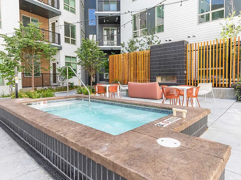 Unwind in the outdoor spa area featuring modern seating, landscaped surroundings, and a cozy fireside gathering space.