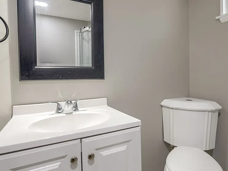Bathroom3 vanity, mirror, overhead light, and corner toilet