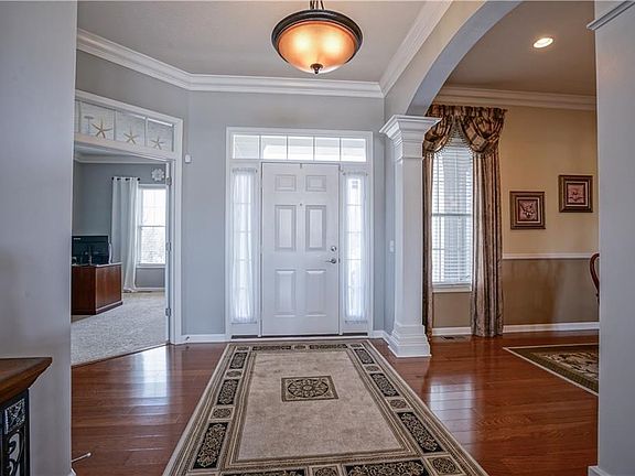 Entry Hall with Crown Molding and hardwood floor draws you in. . . Den/Study with transom window over French Doors and Pillar supported arched entry to Formal Dining are rooms on either side of the Entry.