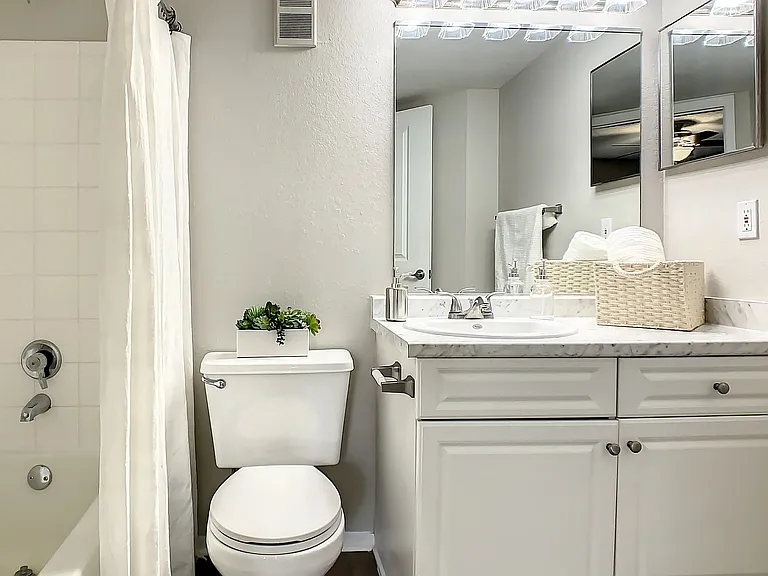 This bathroom features a full tub and shower combo and excellent vanity lighting.
