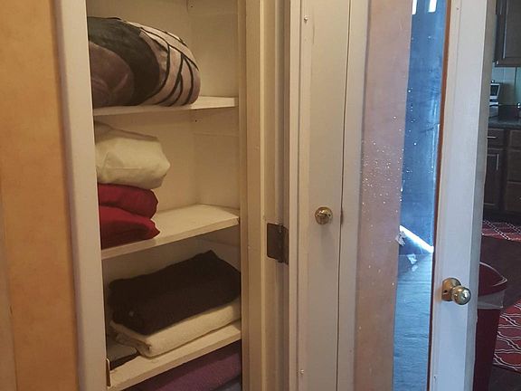 Linen closet with a mirror attached on the door.