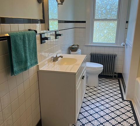 Bathroom with black and white tile floor. Bathroom includes a refinished cast iron tub and shower.