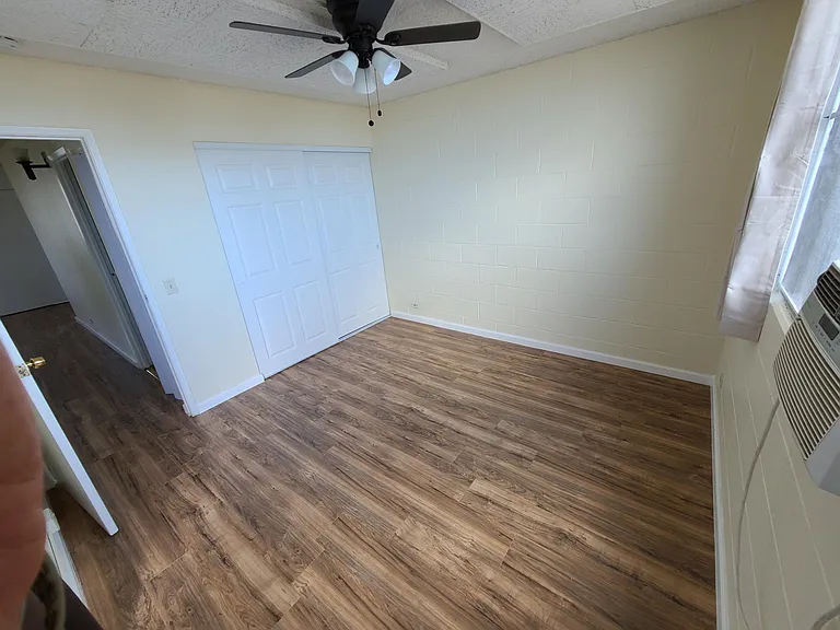Bedroom 1 with sliding closet doors, and window A/C unit. Opening to patio area.