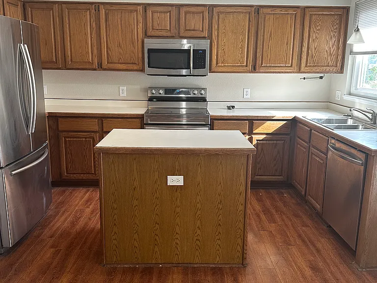 Kitchen with island and stainless appliances including built-in microwave.