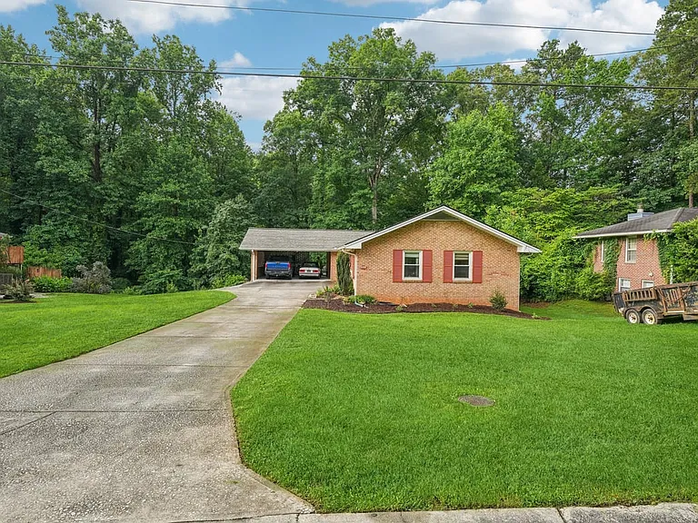 Tucked beneath a canopy of mature trees, this beautifully maintained home feels like a quiet woodland retreat, complete with timeless brick, cheerful shutters, and enchanting curb appeal.