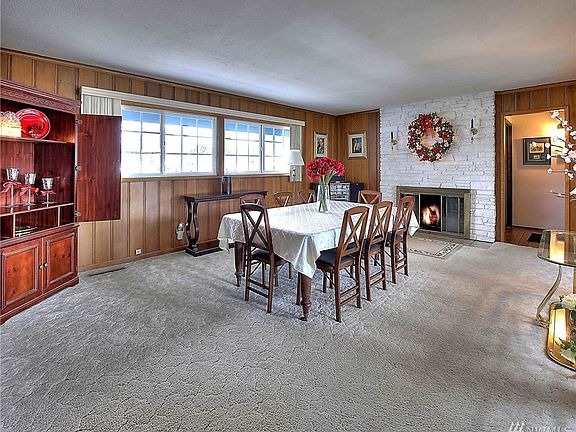 Dining room offers birch wood walls and wood burning fireplace with floor to ceiling stone surround. 