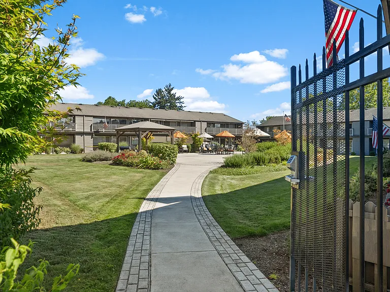A welcoming gated entrance with lush landscaping at Wickshire West Apartments.
