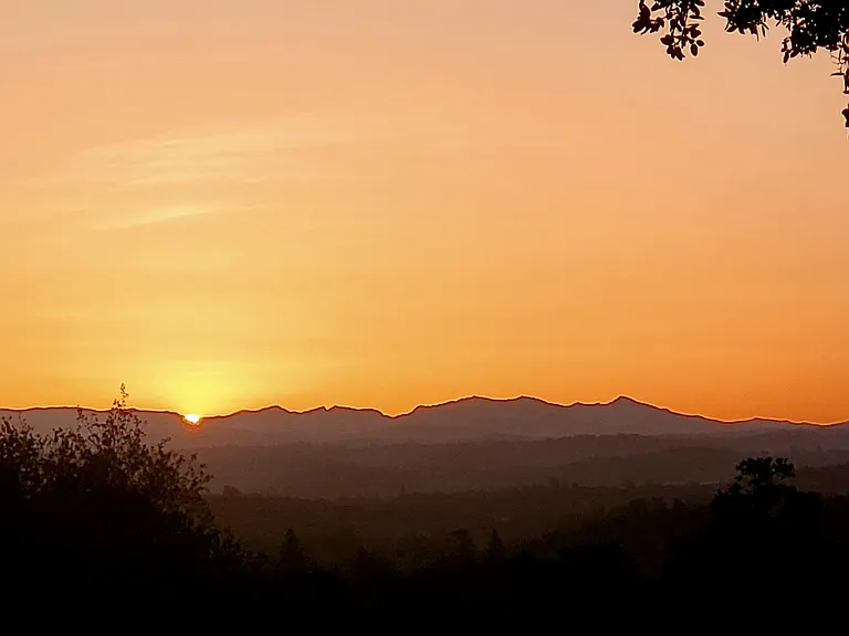 This is a mid-summer sunrise over the great Crystal Range of the Sierras. Lake Tahoe is just on the other side of that deeper saddle (dip) to the right of the sun.