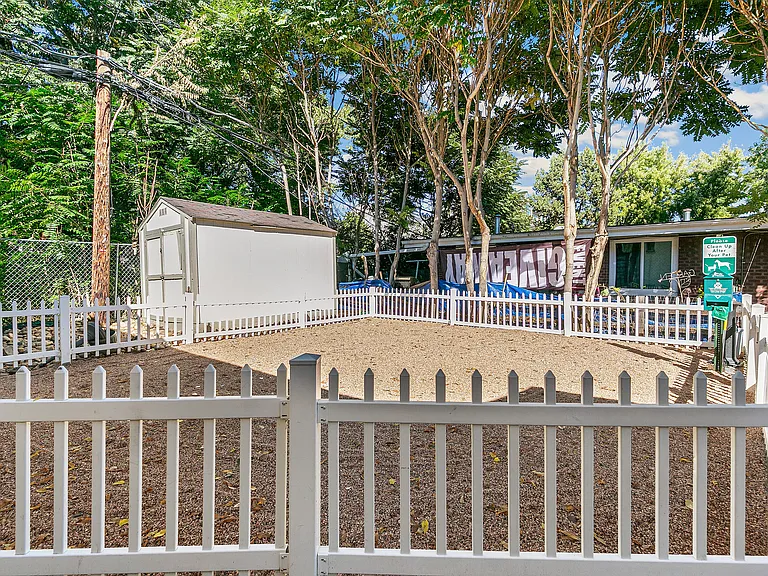 Charming outdoor space with a storage shed, surrounded by a white picket fence and lush greenery.