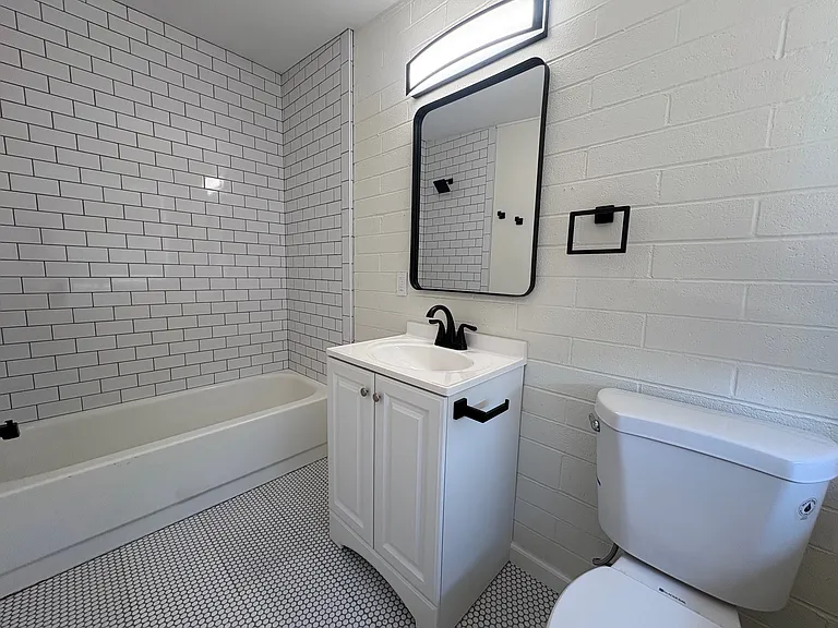 Bathroom with shower / tub combo, new penny tile and subway tile, toilet and vanity.