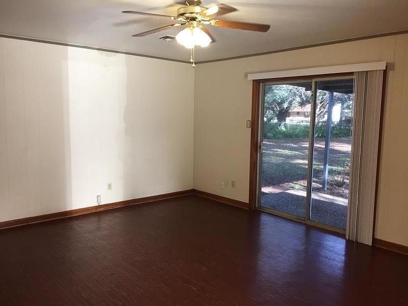 Great room with ceiling fan looking out sliding glass patio door to private park like back yard