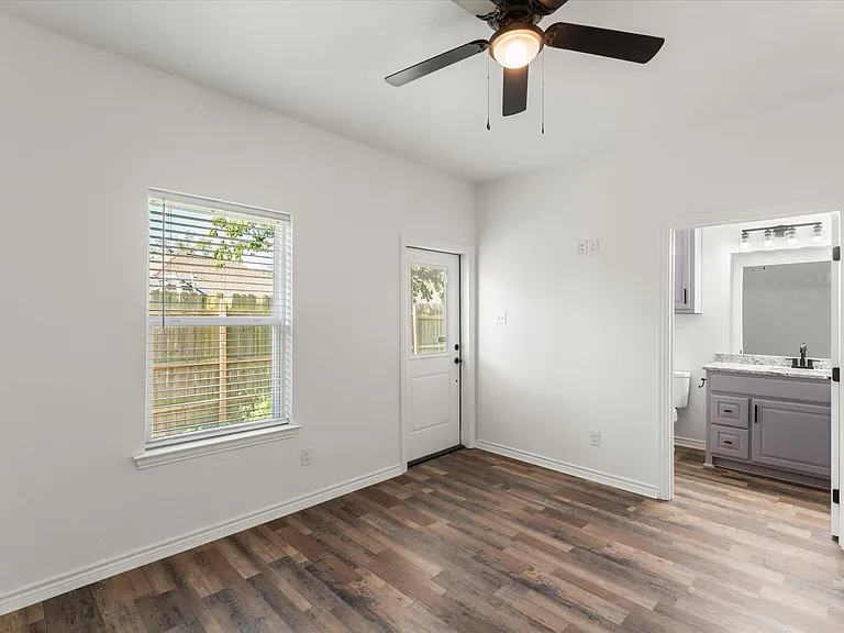 Room featuring wood-finish flooring, a ceiling fan with integrated lighting, and a window with blinds