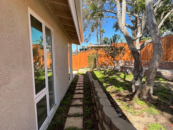 Front walkway over to side patio (also accessible through kitchen and extended driveway). As you can see, entire property is fenced.