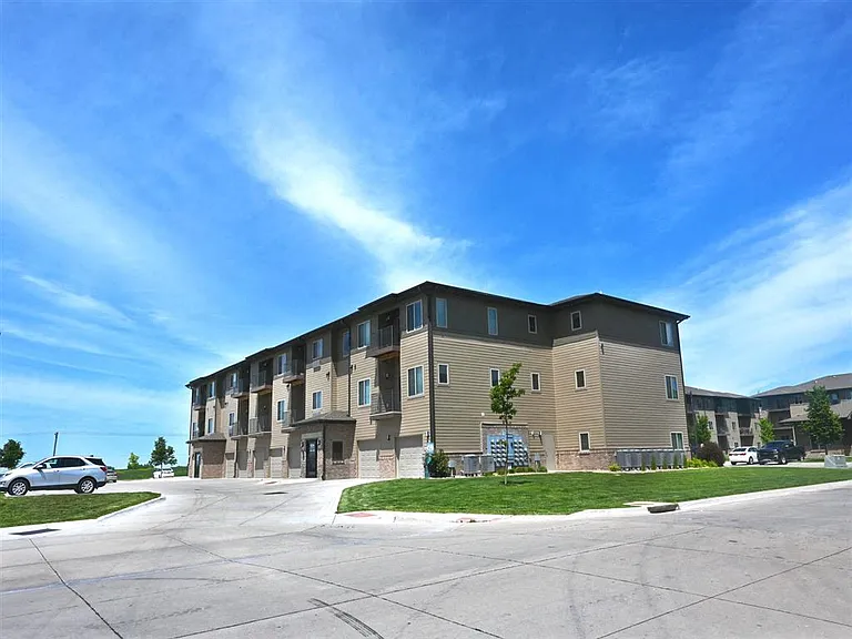 A large apartment building with a parking lot in front at The Sterling Kearney.