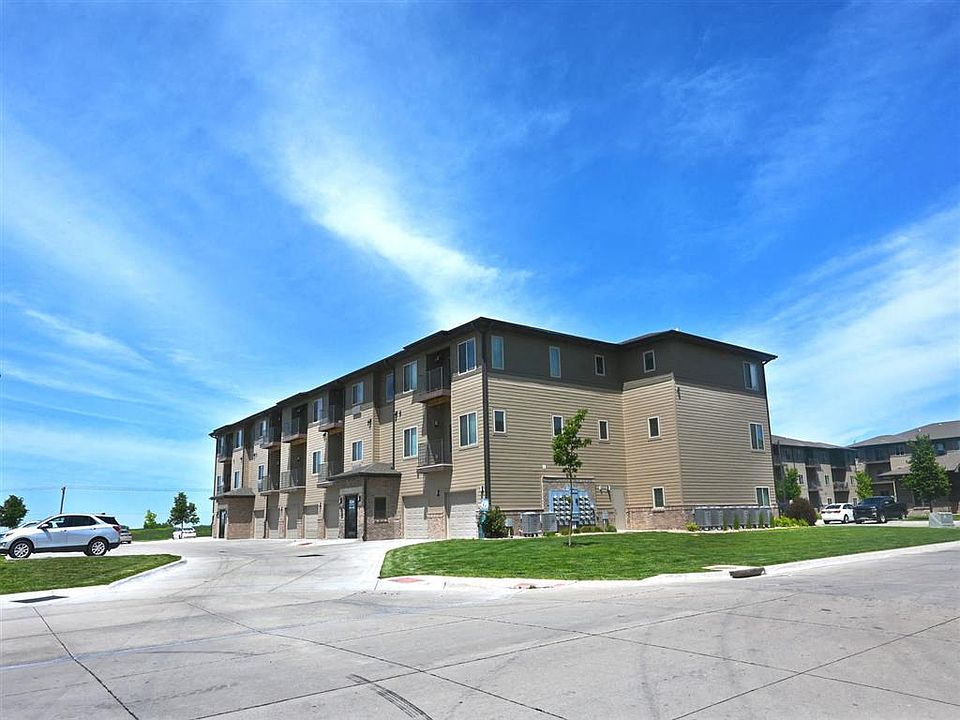 A large apartment building with a parking lot in front at The Sterling Kearney.