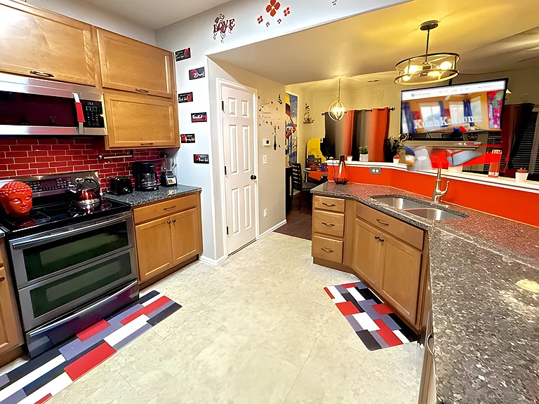 This cozy kitchen features a bold red and black theme with warm cabinetry and artistic, welcoming decor.