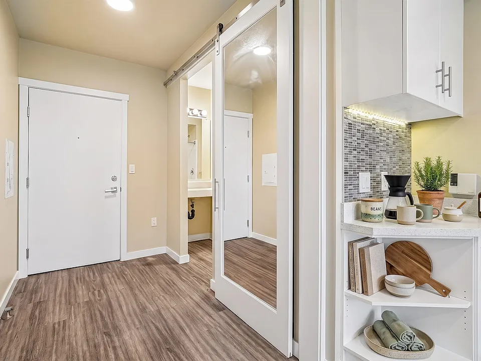 A mirrored sliding door and a corner coffee station make good use of a compact entry.