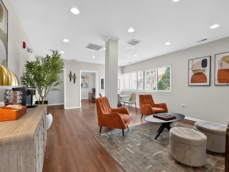 Enjoy a clean, modern community lounge featuring stylish orange seating at Renaissance at Carol Stream in Carol Stream, IL.
