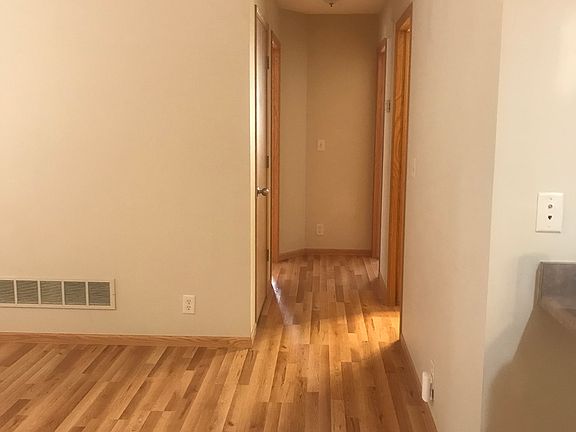 The wood flooring continues throughout the condo; this hallway leads to the bathroom and two bedrooms.
