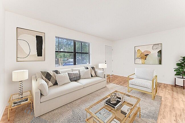 Bright and inviting living room with modern decor, featuring a plush white sofa, elegant artwork, and warm wood flooring.