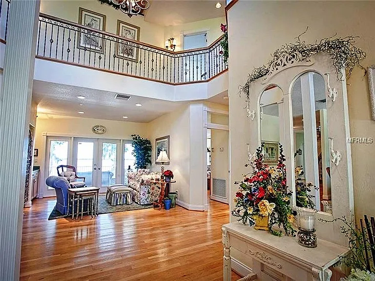 This is the two story foyer looking out to the main screened porch overlooking the lake and pool deck. The upper balcony connects the upper BRs and craft rooms.