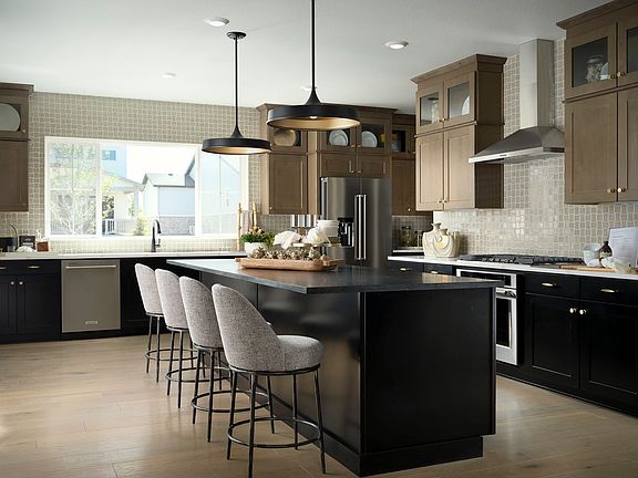 A modern and spacious kitchen with a large central island, dark cabinets, and pendant lighting fixtu