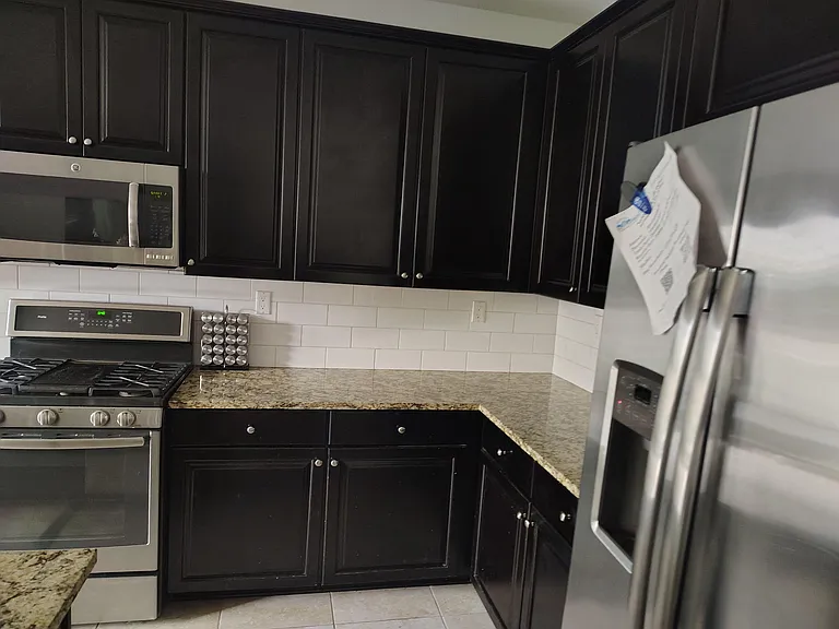 Kitchen features granite countertops, ample cabinet storage, and stainless-steel appliances with a subway-tile backsplash.