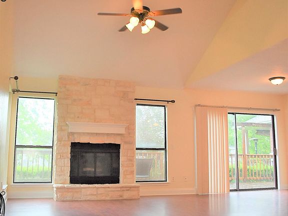 View of living room from front door showing ceiling fan and fireplace.