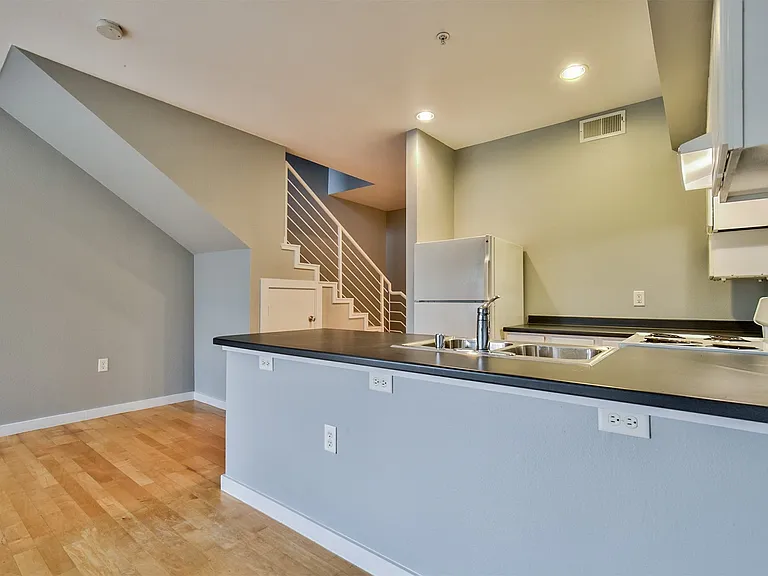 Contemporary kitchen area featuring a prominent peninsula with a double basin stainless steel sink and a built-in electric stovetop