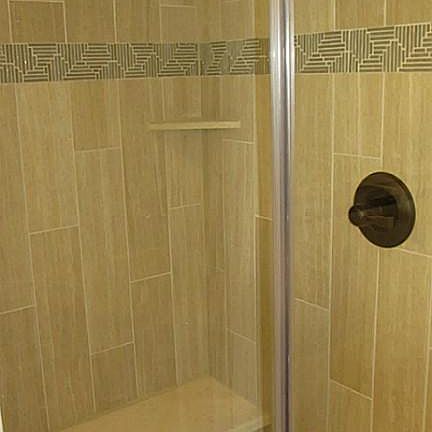 Floor to ceiling tiled stand up shower with built-in bench .