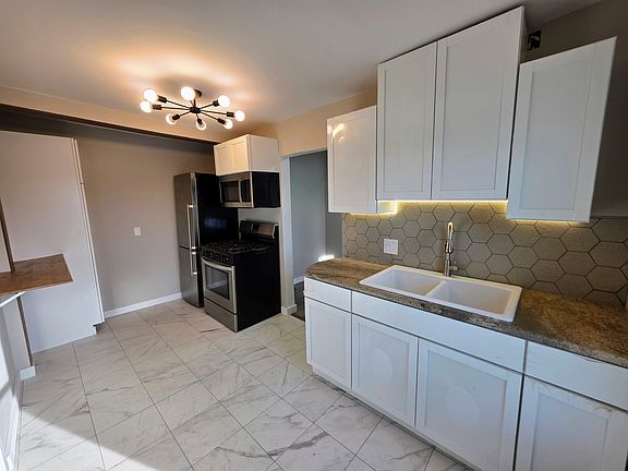 Brand new kitchen with polished granite counters, deep double sink, tile backsplash and backlight. (Cabinets still have protective wrap)