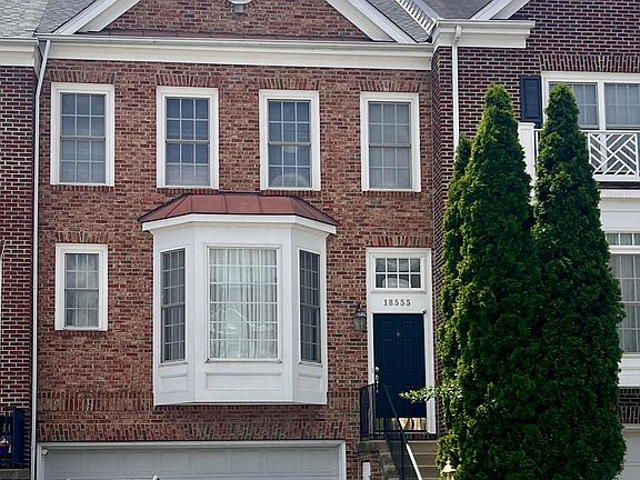 The front view features a beautiful brick exterior, a charming bay window with PVC frames, a welcoming entry with steps leading to the front door, and two-car garage.