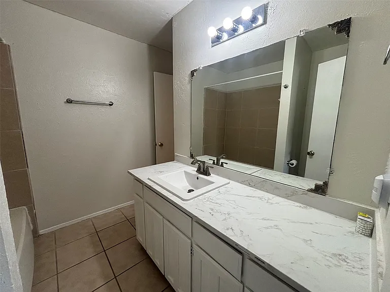 White vanity with shaker-style cabinetry, an integrated sink, and a marbled countertop