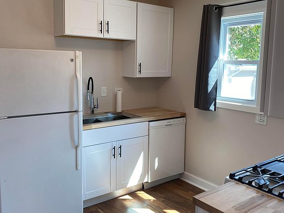 Kitchen with stove, microwave, refrigerator, garbage disposal, double sink and butcher block countertops,