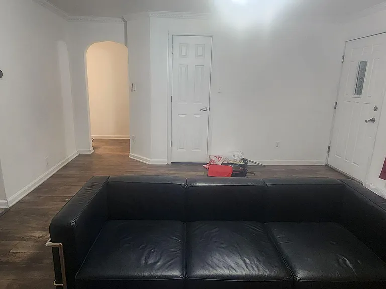 Open living area with wood-style flooring, arched entryway, and convenient access to the front door and nearby rooms.