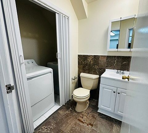 Half bath with updated cabinet, vanity and fixtures off of kitchen on first floor with brand new in unit washer & dryer