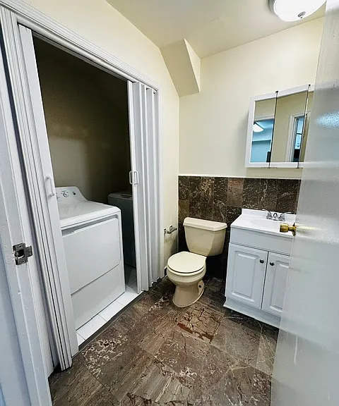 Half bath with updated cabinet, vanity and fixtures off of kitchen on first floor with brand new in unit washer & dryer