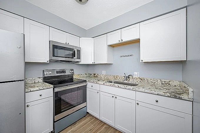 Modern kitchen with sleek stainless steel appliances, elegant granite countertops, and stylish white cabinetry.
