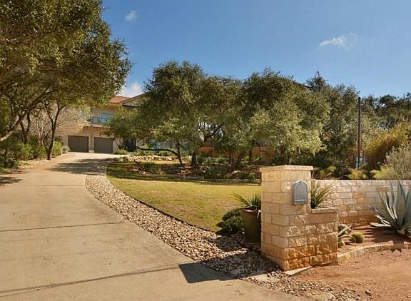 Large trees shade the yard and a privacy wall is outside of the home.