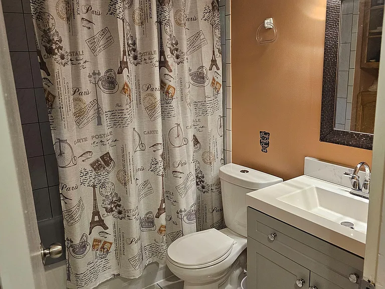 Full bathroom with tiled tub/shower, vanity with storage, and framed mirror for daily routines.