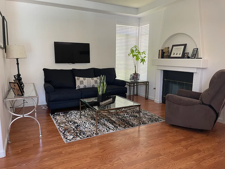 Bright living space with a classic fireplace, featuring double French doors for effortless patio access.