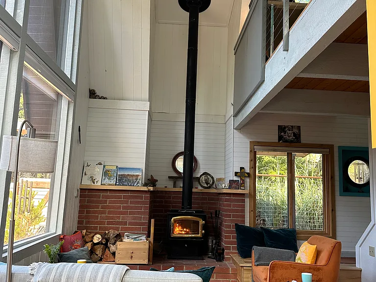 Cozy woodstove, upstairs loft area and step through window to the covered deck and access to woodshed
