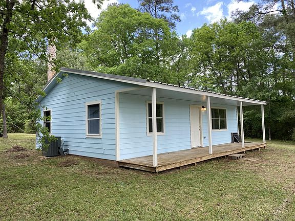 View of back of home with sprawling covered porch to park a couple of rocking chairs.