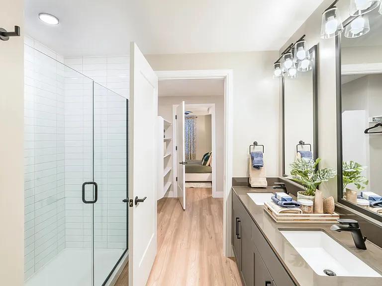Sleek dual vanities and glass showers in select homes, paired with modern lighting and refined designer touches.
